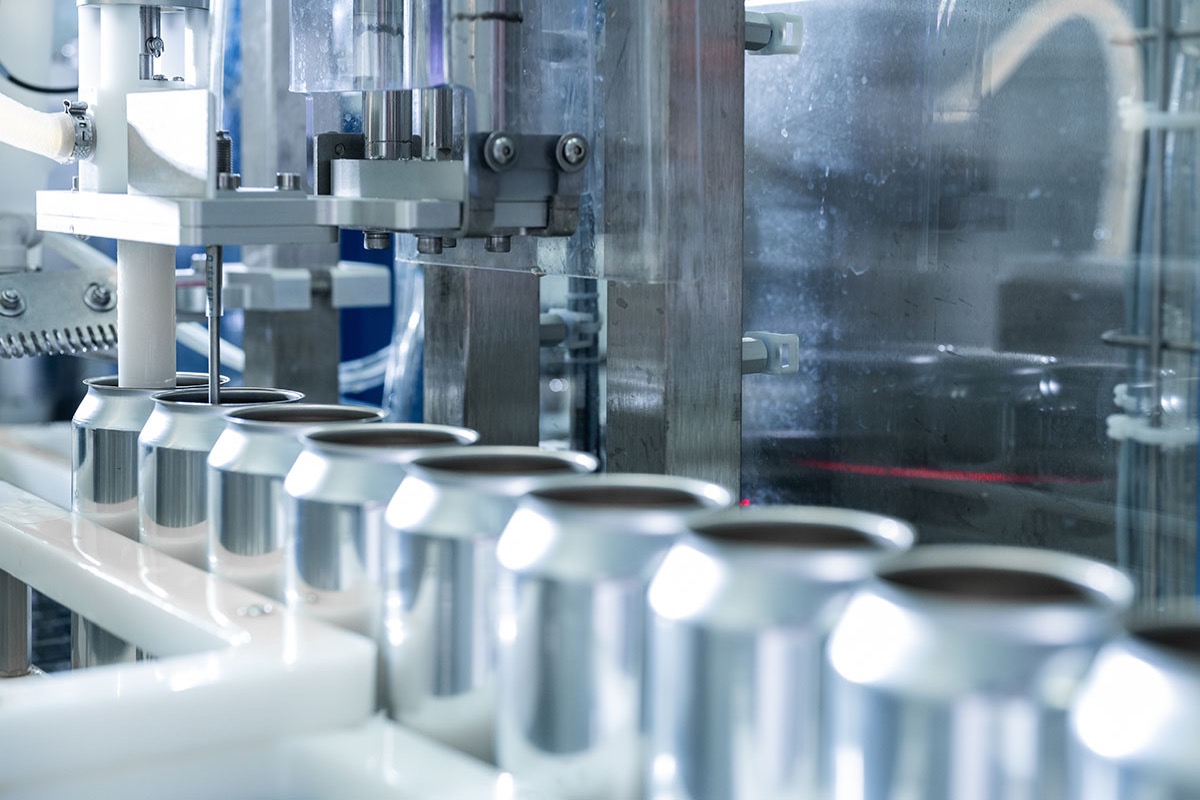 Empty aluminium cans moving in a row along a filling line in a beverage plant
