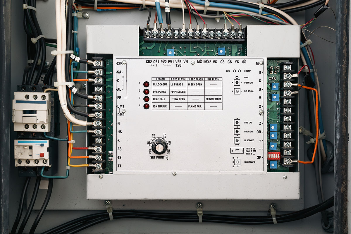 An open electrical enclosure showing a temperature control board with a set point dial, status LEDs and rows of wired terminal blocks beside two contactors