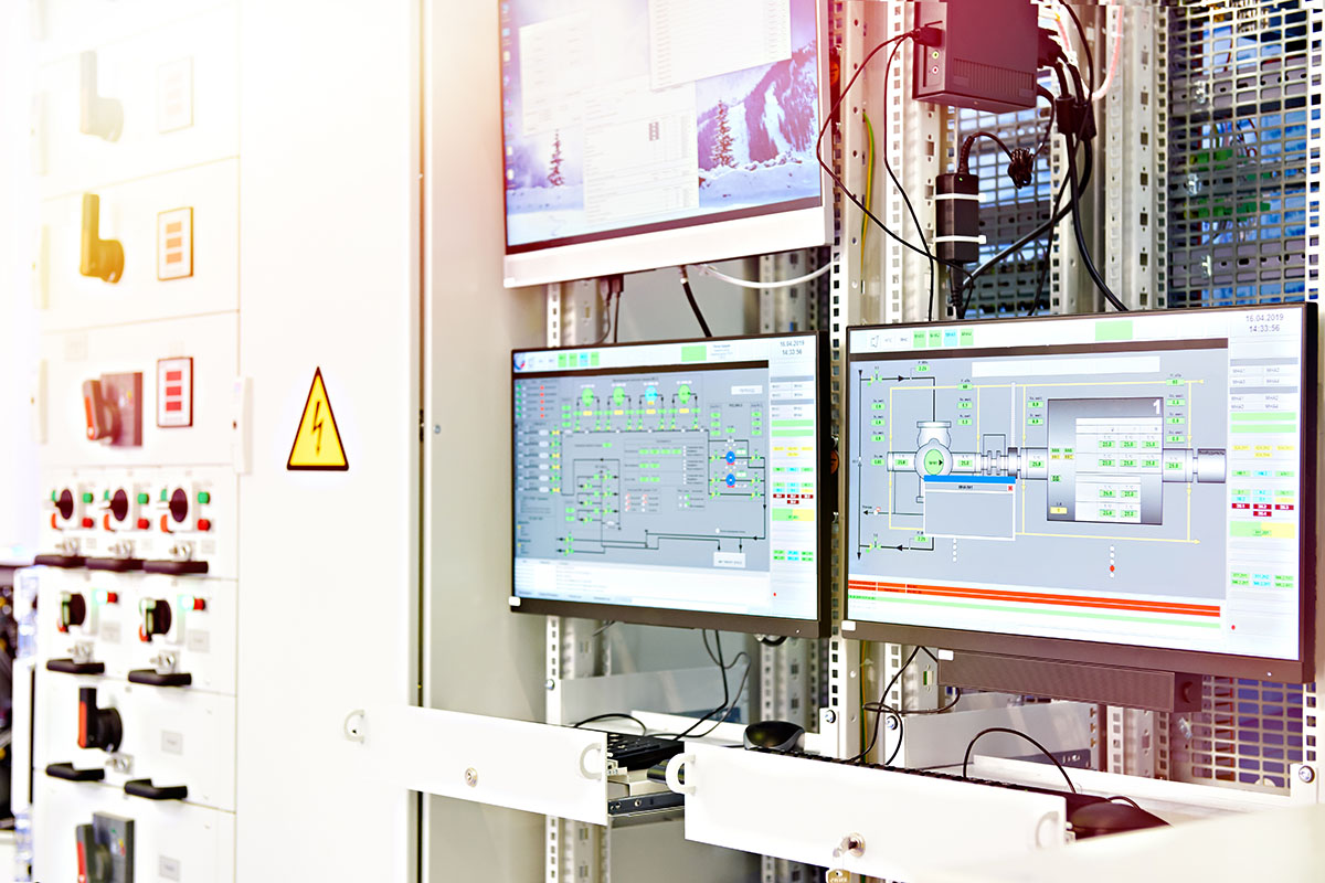 Process control screens and an electrical control panel inside an industrial plant